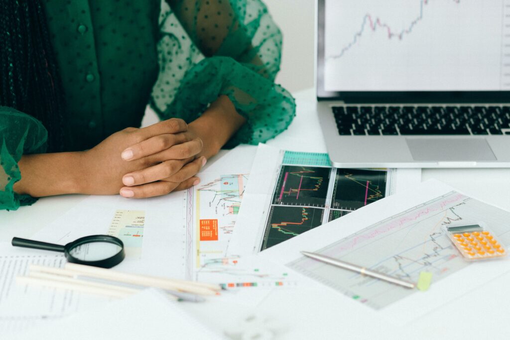 Consulente finanziario che analizza grafici di mercato, dati e tassi ipotecari su laptop e documenti.